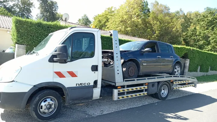 Renault Mégane avec des éléments avant absents sur une dépanneuse.
