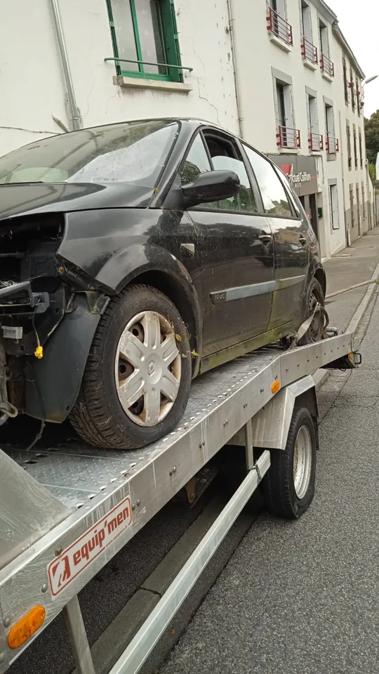 Renault Scénic avec des éléments avant absents sur une dépanneuse.