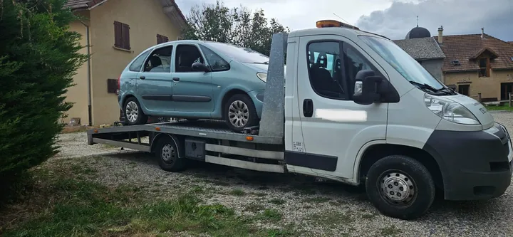 Citroën Xsara Picasso chargé sur une dépanneuse devant une maison.