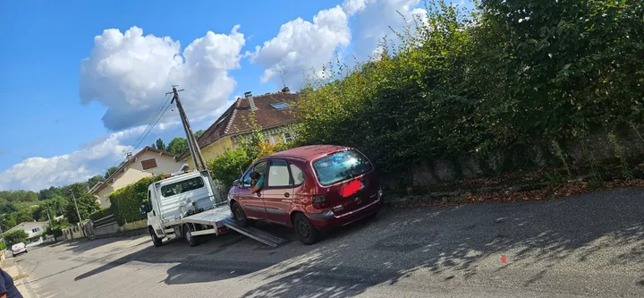 Renault Scénic au sol près du plateau abaissé d’un camion.