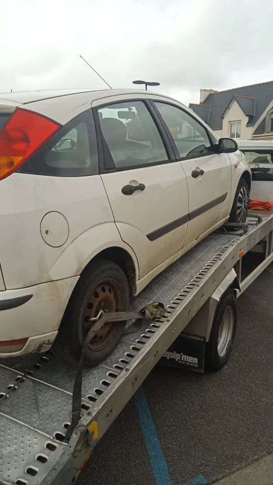 Ford Focus sur un plateau avec une sangle fixée à une roue arrière.