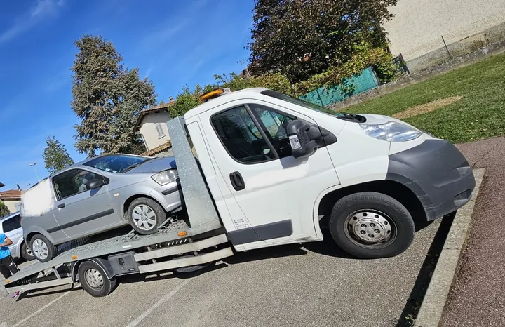Citadine à trois portes chargée derrière la cabine d’une dépanneuse.