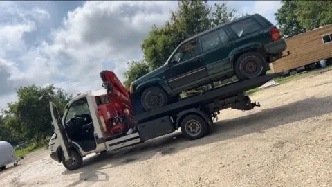 Grand véhicule tout terrain chargé sur un camion à grue rouge.