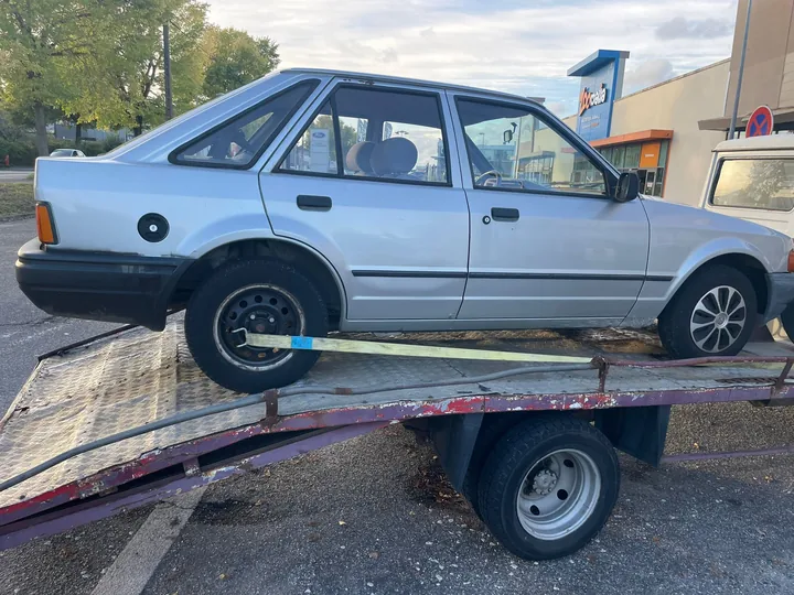 Berline claire sur une plateforme avec une sangle au niveau d’une roue.