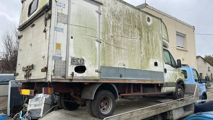 Utilitaire à caisse haute aux parois marquées sur un camion plateau.