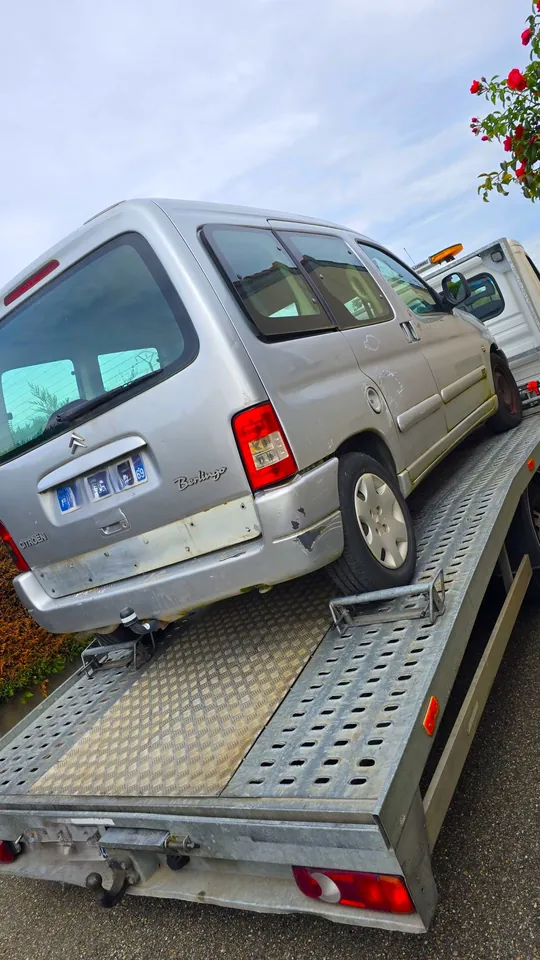 Véhicule familial clair sur un plateau métallique avec une sangle près des roues.