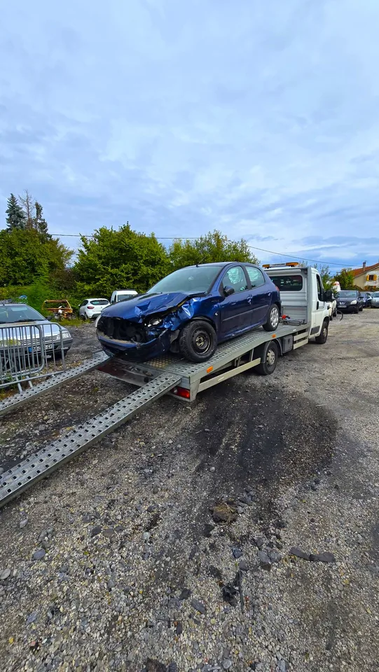 Voiture sombre à l’avant déformé sur un plateau avec deux rampes déployées.