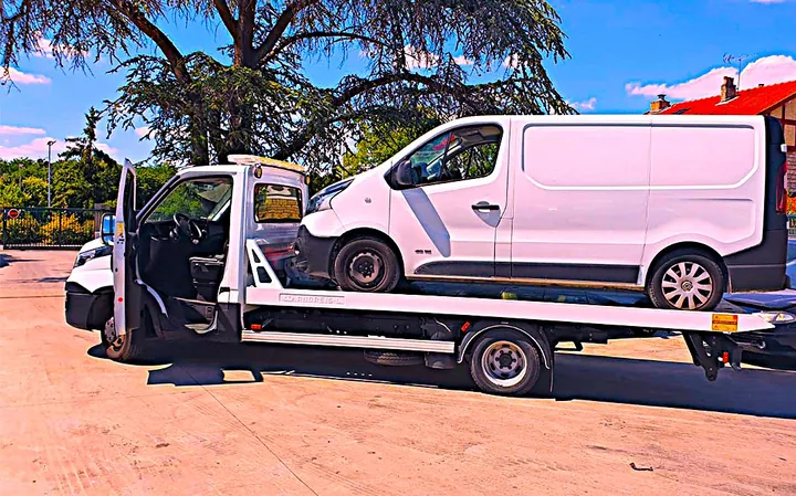 Fourgonnette blanche à carrosserie fermée sur un camion plateau.