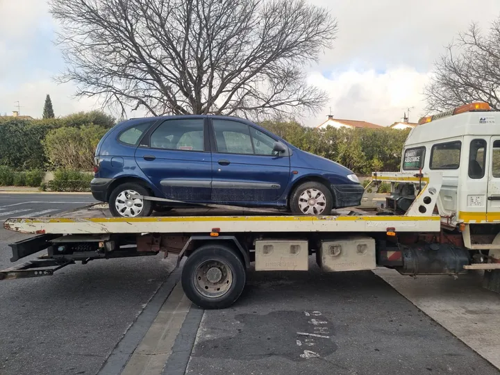 Petite voiture familiale bleue installée sur le plateau d’un camion.