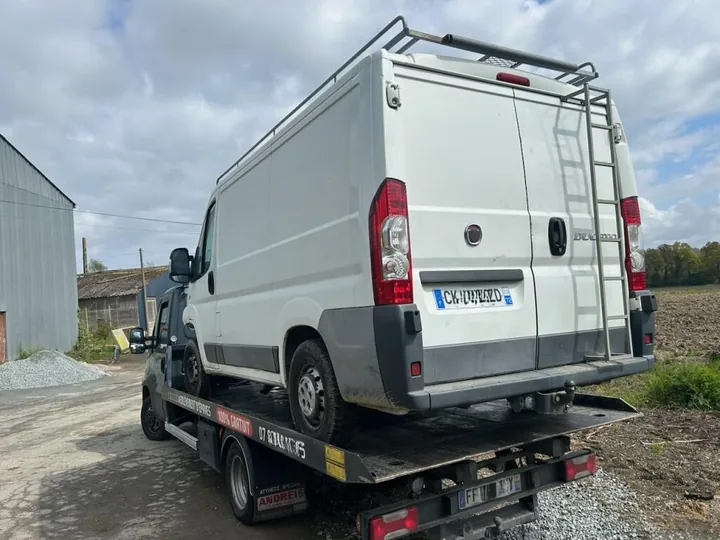 Fourgon blanc à toit haut sur le plateau d’un camion.