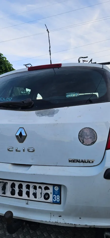 Arrière d’une Renault Clio blanche au hayon marqué, sur un plateau.