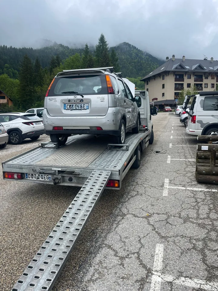 Monospace clair sur une dépanneuse avec une rampe déployée dans une rue.