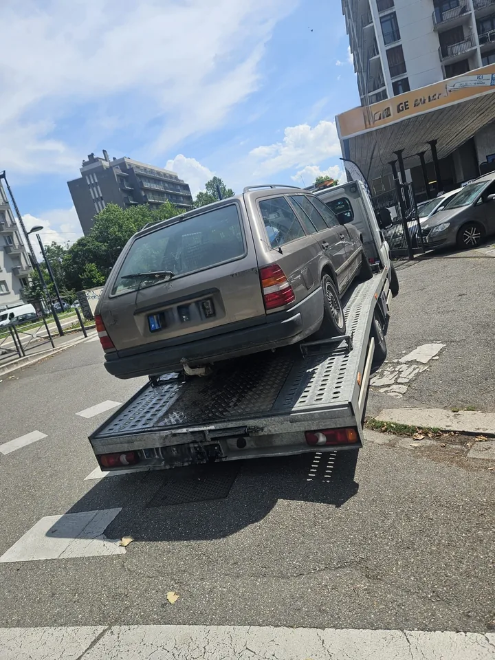 Arrière d’un break ancien chargé sur un plateau près d’immeubles.