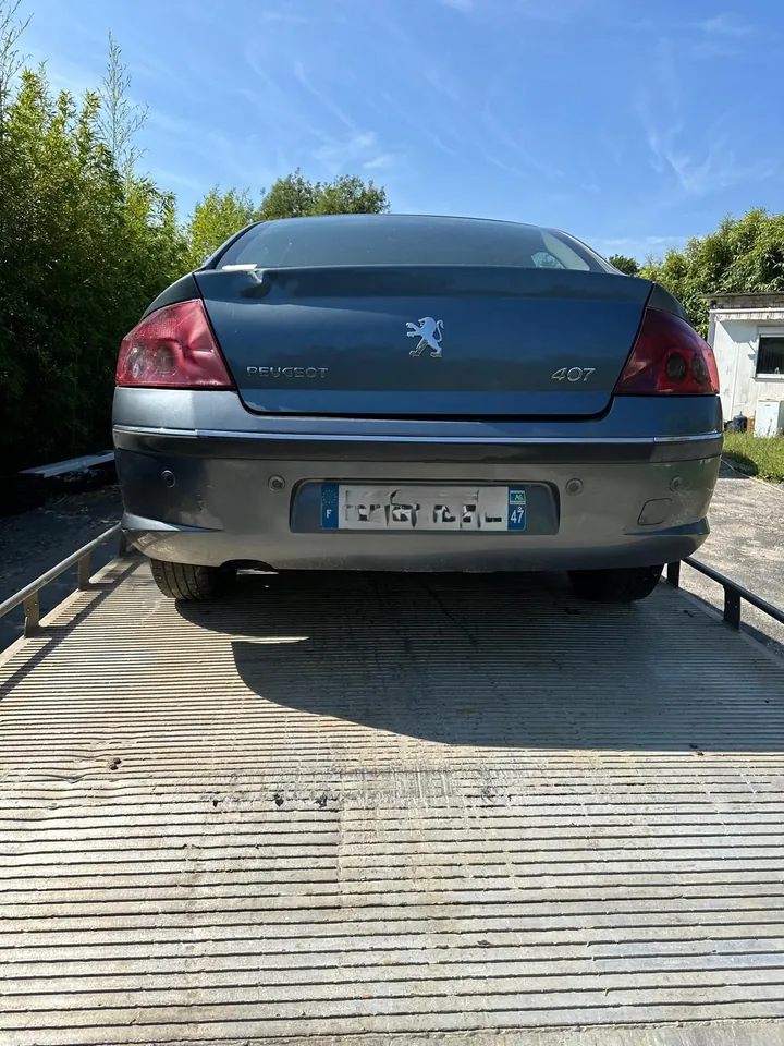 Arrière d’une Peugeot 407 chargée sur la surface métallique d’une dépanneuse.