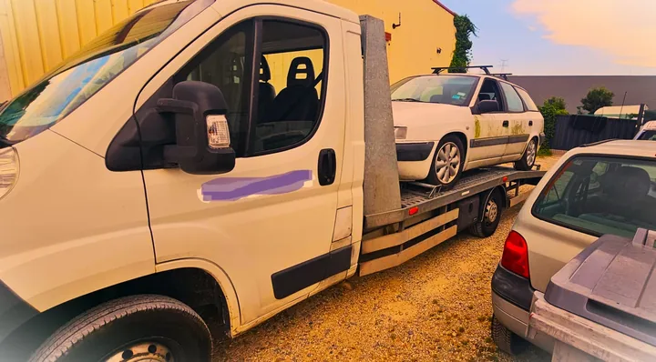 Voiture compacte claire sur une dépanneuse, entre d’autres véhicules.